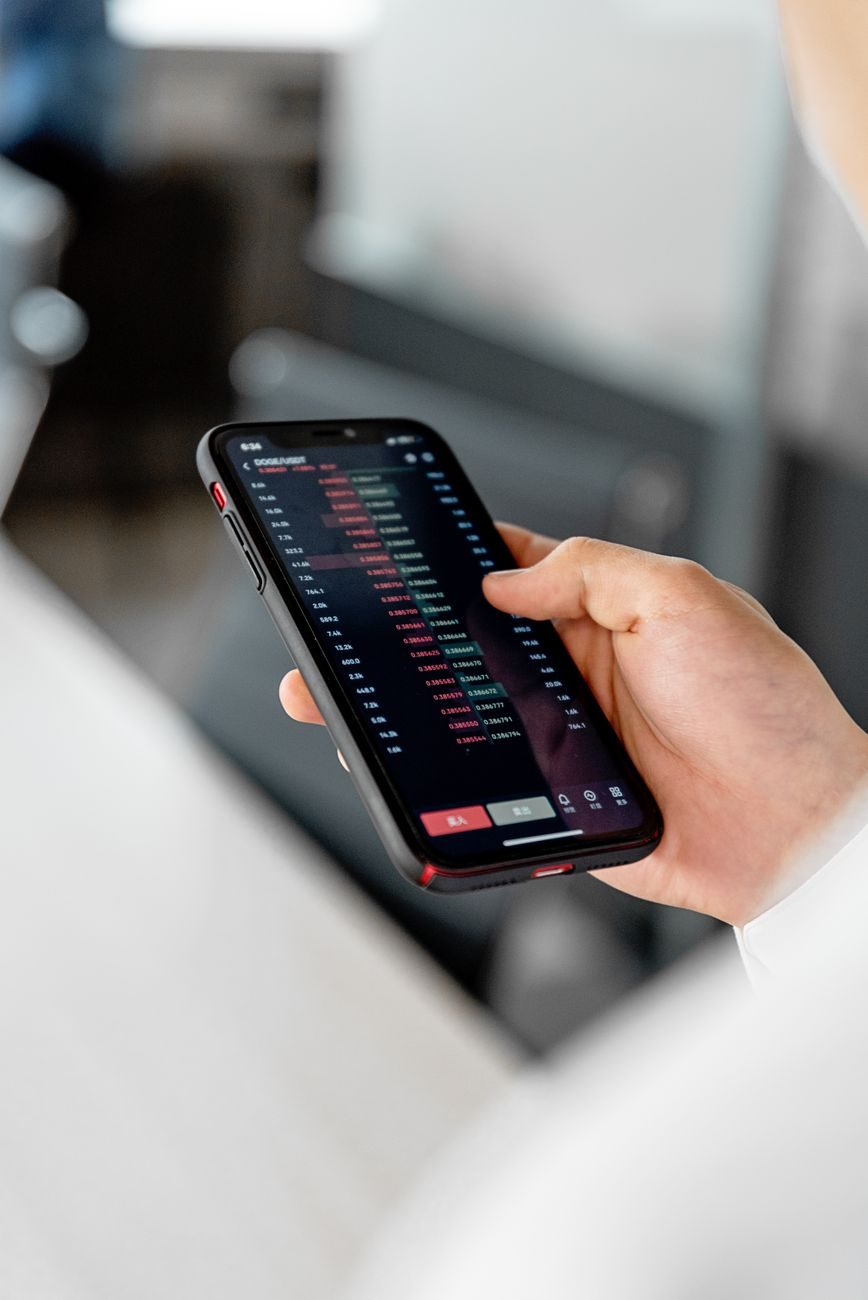 A hand holding a phone showing a financial trading application