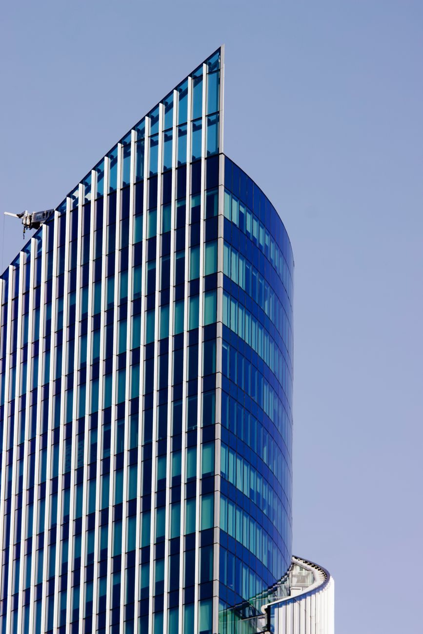 A blue glass office tower seen from below